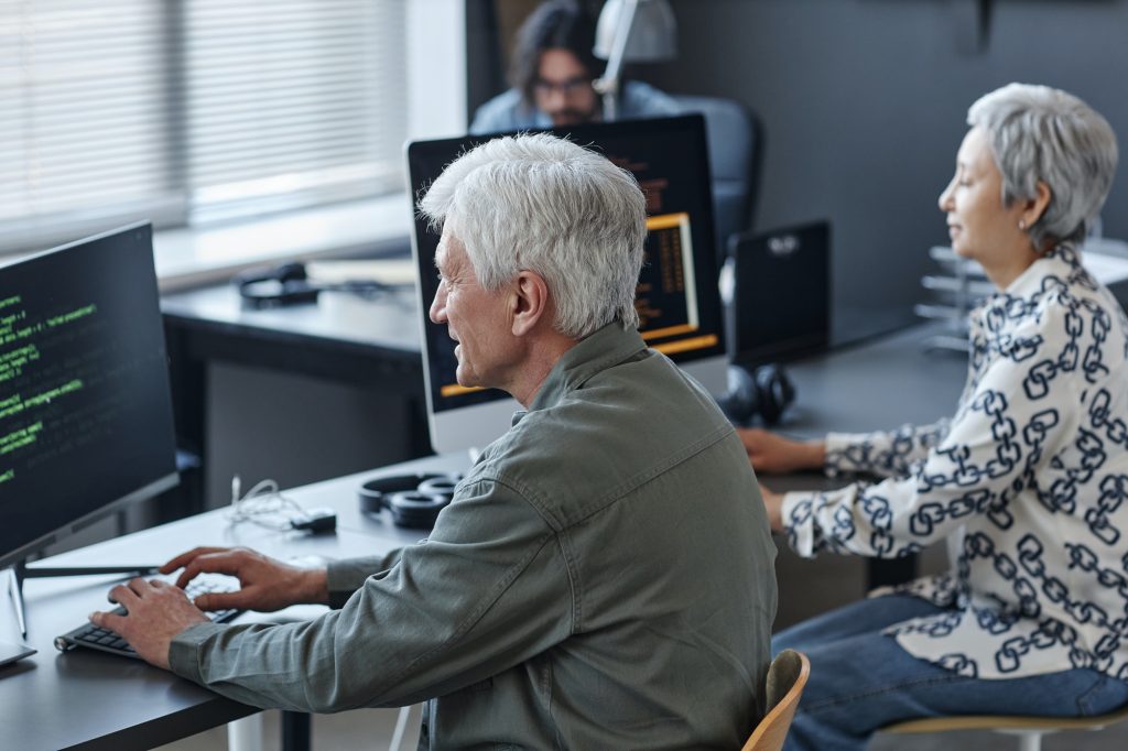 White haired man using computer in coding class for elderly